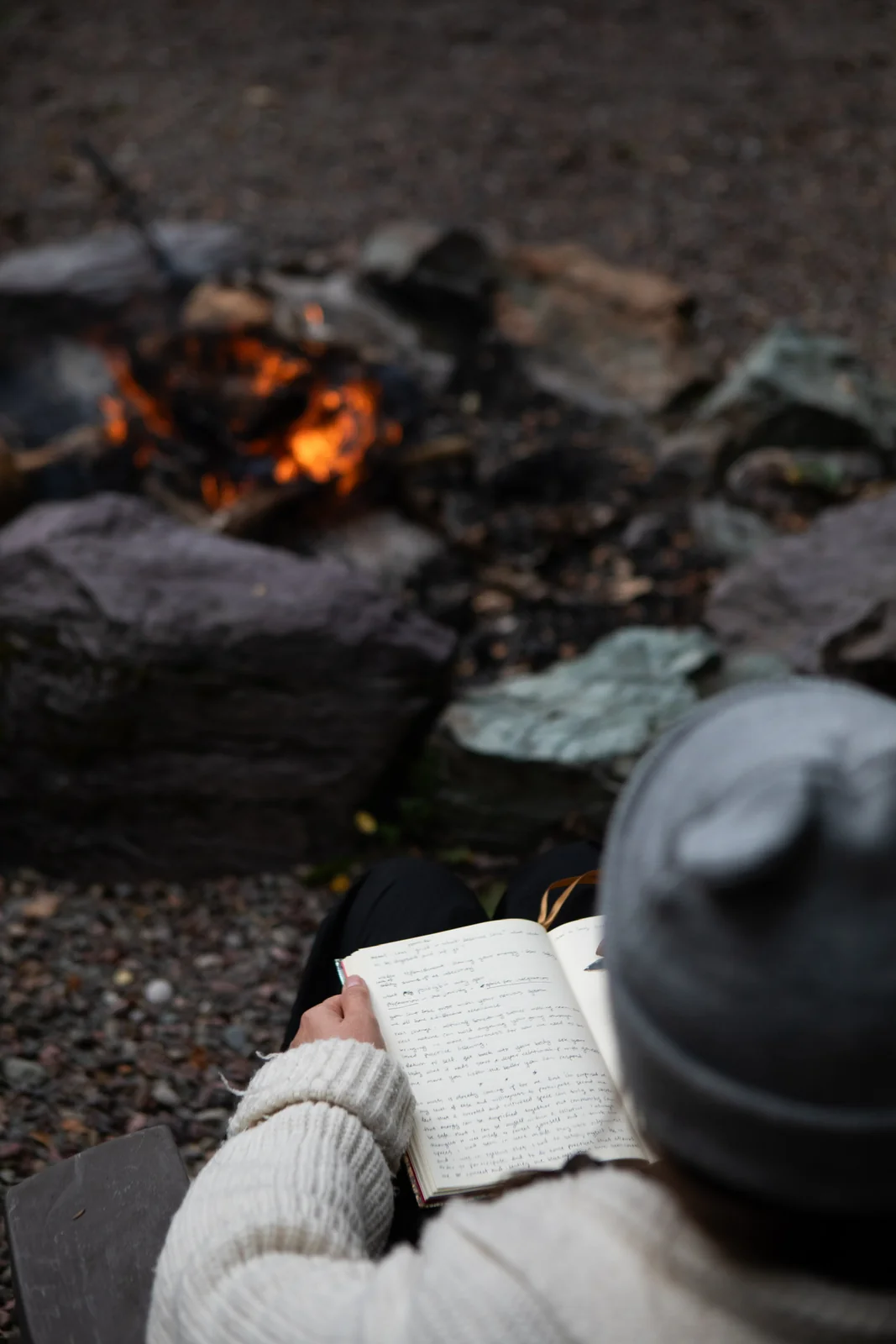 A guest with a journal beside an outdoor fire