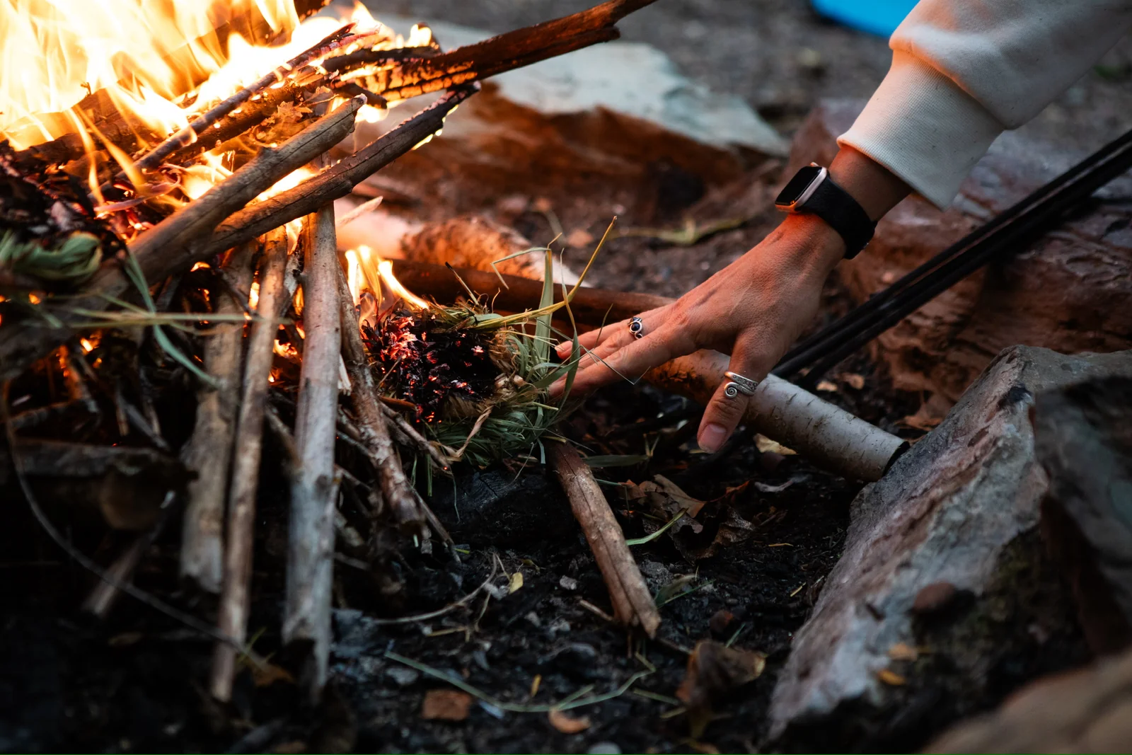 Hands tending a small outdoor fire