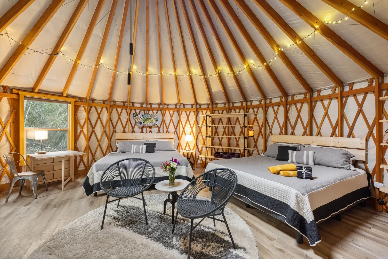 Yurt interior with beds and seating beneath its timber roof